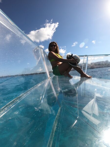 Chica disfrutando del sol en la proa de barco transparente cozumel en una tarde soleada y sonriente disfrutando sus vacaciones en cozumel