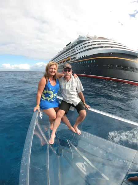 pareja de adultos mayores celabrando en cozumel con el crucero de disney al fondo, como aprte del tan buscado tour barco transparente cozumel