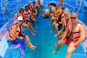 grupo de turistas con una vista submarina abordo de un barco de cristal