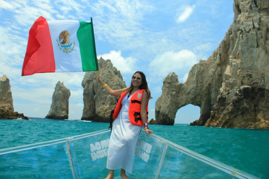 Discover Paradise: Your Clear Boat Tour to Lover's Beach in Los Cabos 2 mujer en vestido blanco sonriendo orgullosa con la bandera de mexico