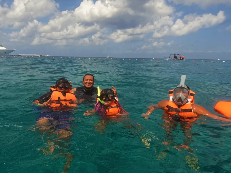 A happy family with kids snorkeling in the water as part of their family tour in Cozumel.