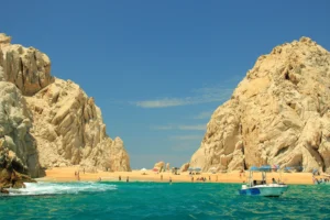 A stunning view from the water of the iconic Lover's Beach in Los Cabos, framed by massive rock formations, as seen during a clear boat tour.