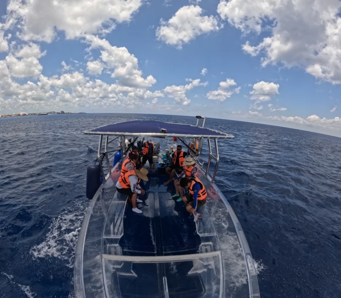 Una Aventura para Todos: El Mejor Tour Familiar en Cozumel 5 Vista panorámica de la lancha transparente navegando en el mar Caribe con un grupo de turistas disfrutando del paseo.