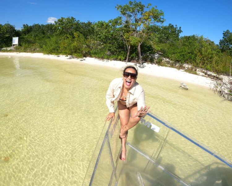 A woman smiling on the bow of a transparent boat at a shallow beach in Nichupté Lagoon, optimized for Cancun World Cup 2026.