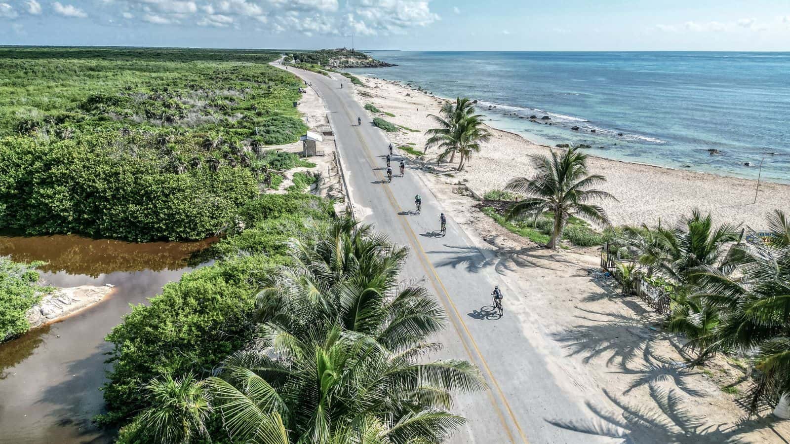 Cyclists riding along the Caribbean coast of Cozumel during IRONMAN race week