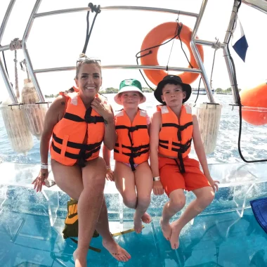 mama e hijos conociendo la naturaleza en un alancha de cristal en cozumel